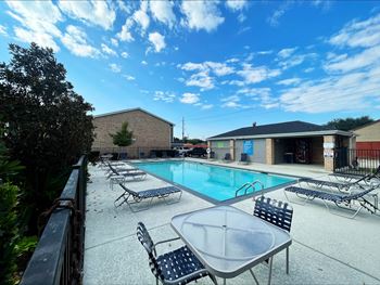 Swimming pool area with lounge chairs and amenity building